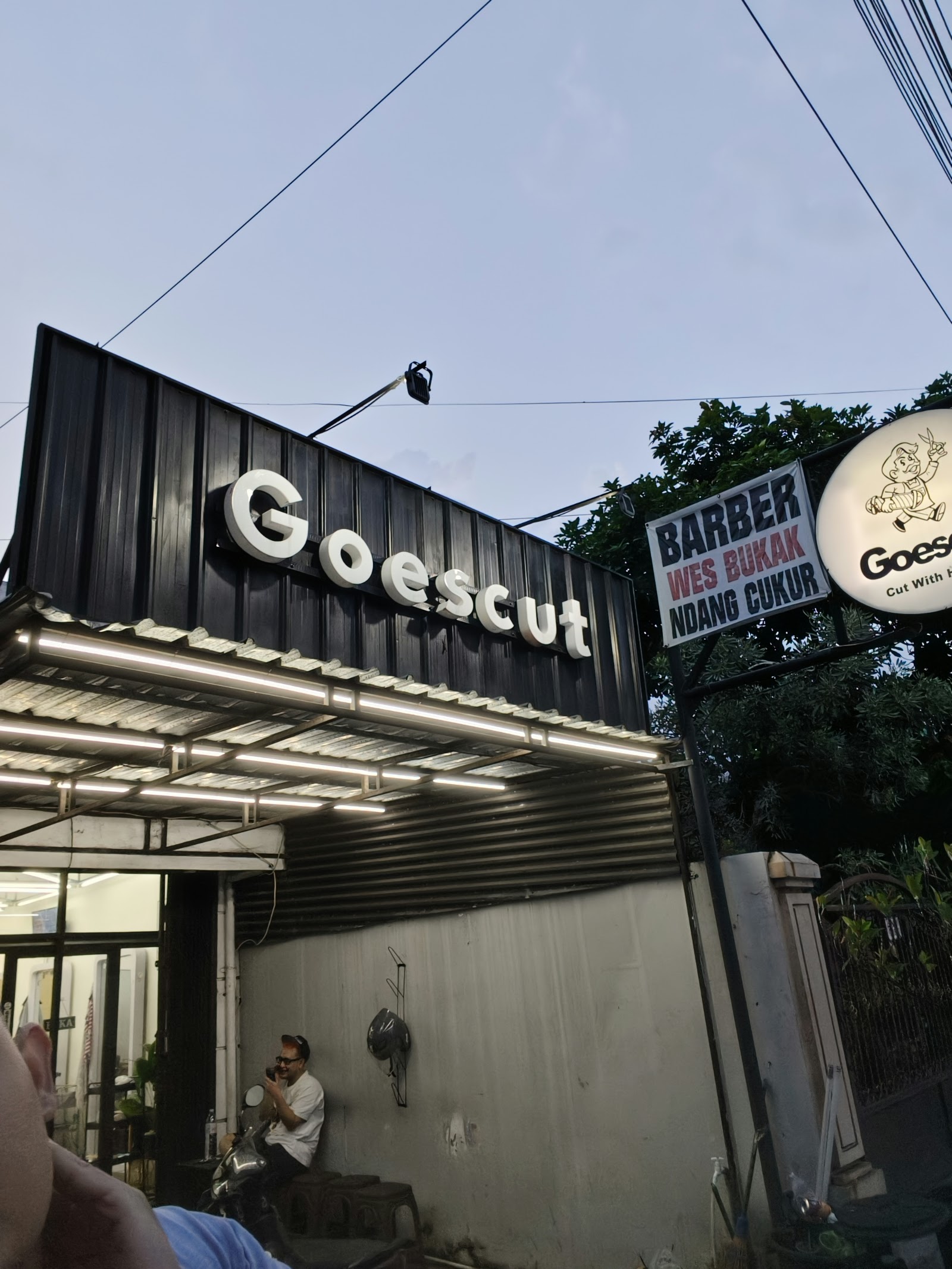 Papan nama GoesCut pada fasad barbershop Condongcatur saat menjelang malam